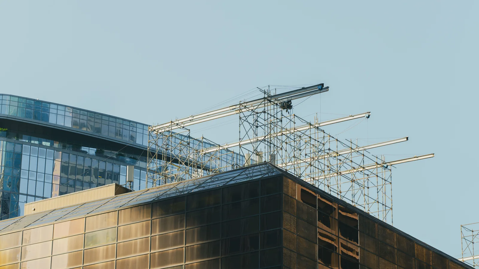 Rooftop scaffolding and projecting steel beams above glass-fronted buildings in Houston.